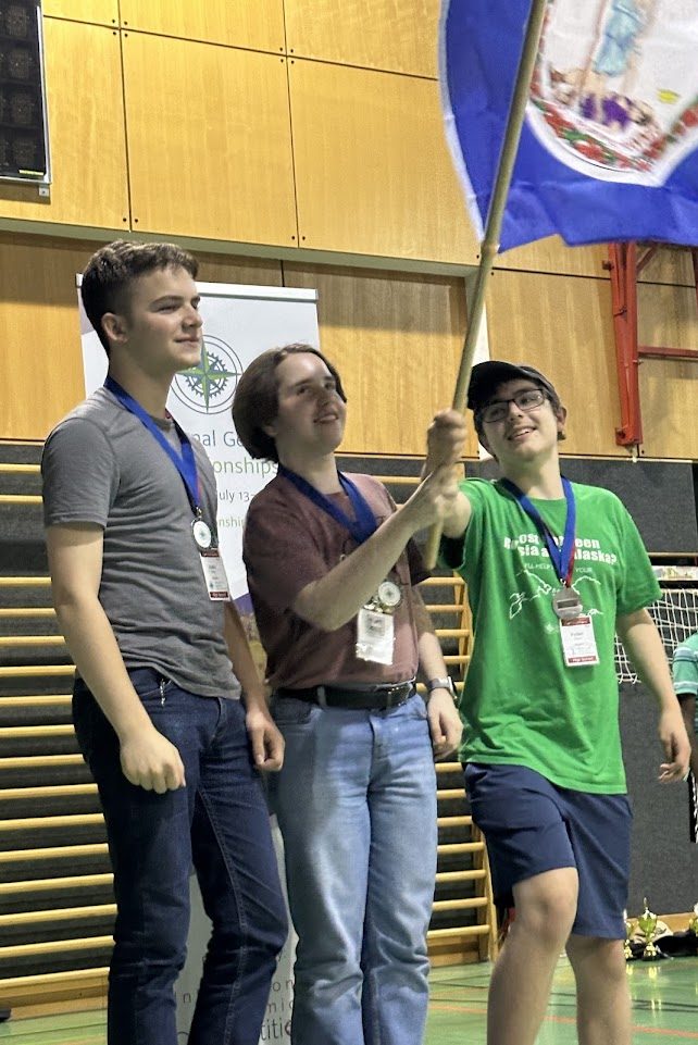 Minton, standing in the middle with a brown shirt, holds the Virginia state flag with his teammates from the Geographeud competition. Minton was the captain of the Virginia B team, which placed second place in the competition.